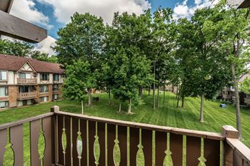 A balcony overlooks a grassy area with trees